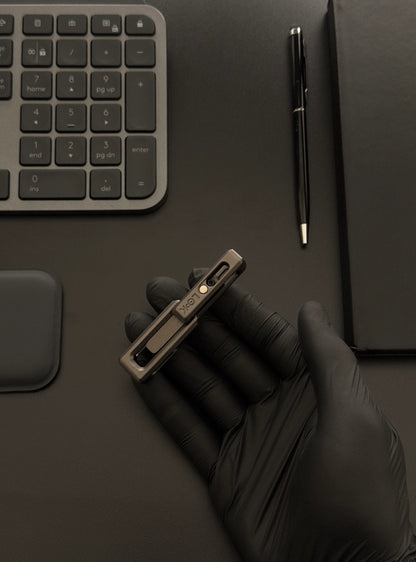 xLock Tower Fidget held in hand on a desk alongside a keyboard and notebook, illustrating its compact size and suitability for workspace use.​