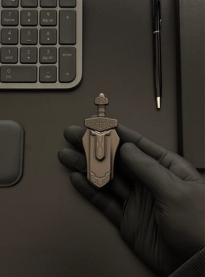 Magnetic Sword Slider in hand on a desk alongside a keyboard and notebook.