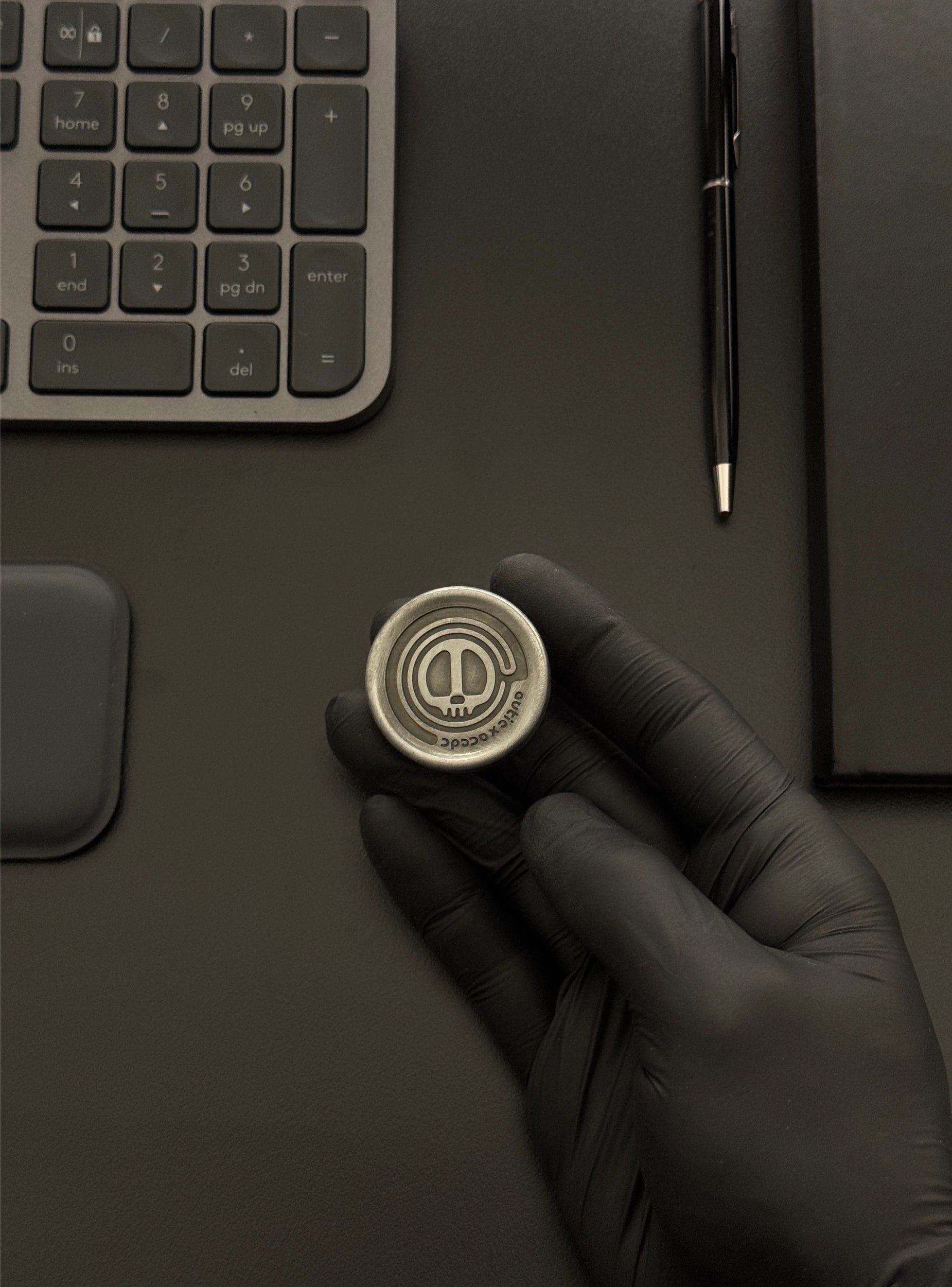 The Skull Coin being used on a desktop next to a keyboard and notebook, demonstrating its integration into a modern workspace.
