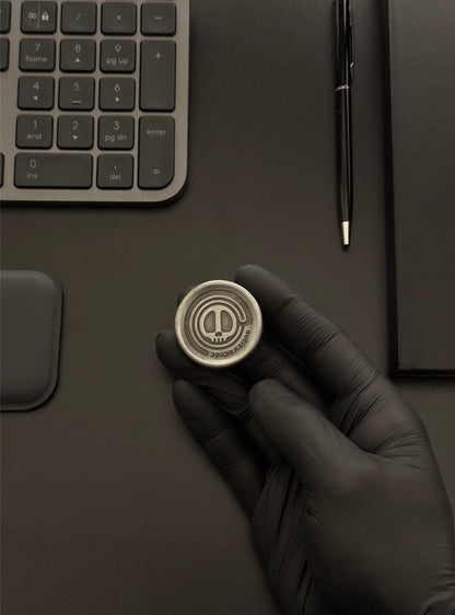 The Skull Coin being used on a desktop next to a keyboard and notebook, demonstrating its integration into a modern workspace.
