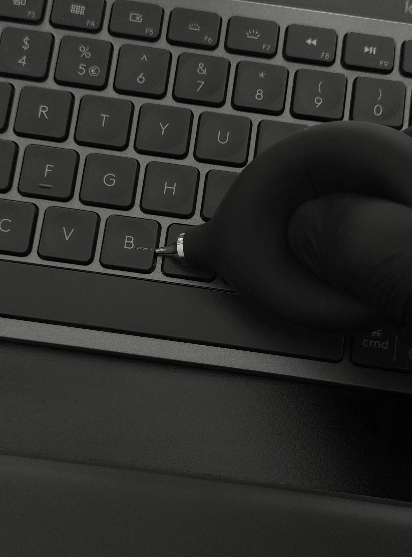 Precision Air Blower held in hand above a desk with a keyboard and notebook, demonstrating practical size and everyday usability