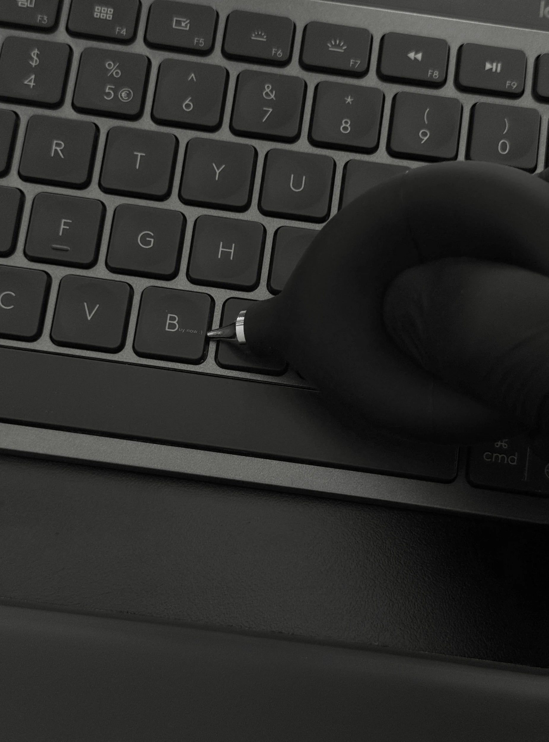 Precision Air Blower held in hand above a desk with a keyboard and notebook, demonstrating practical size and everyday usability