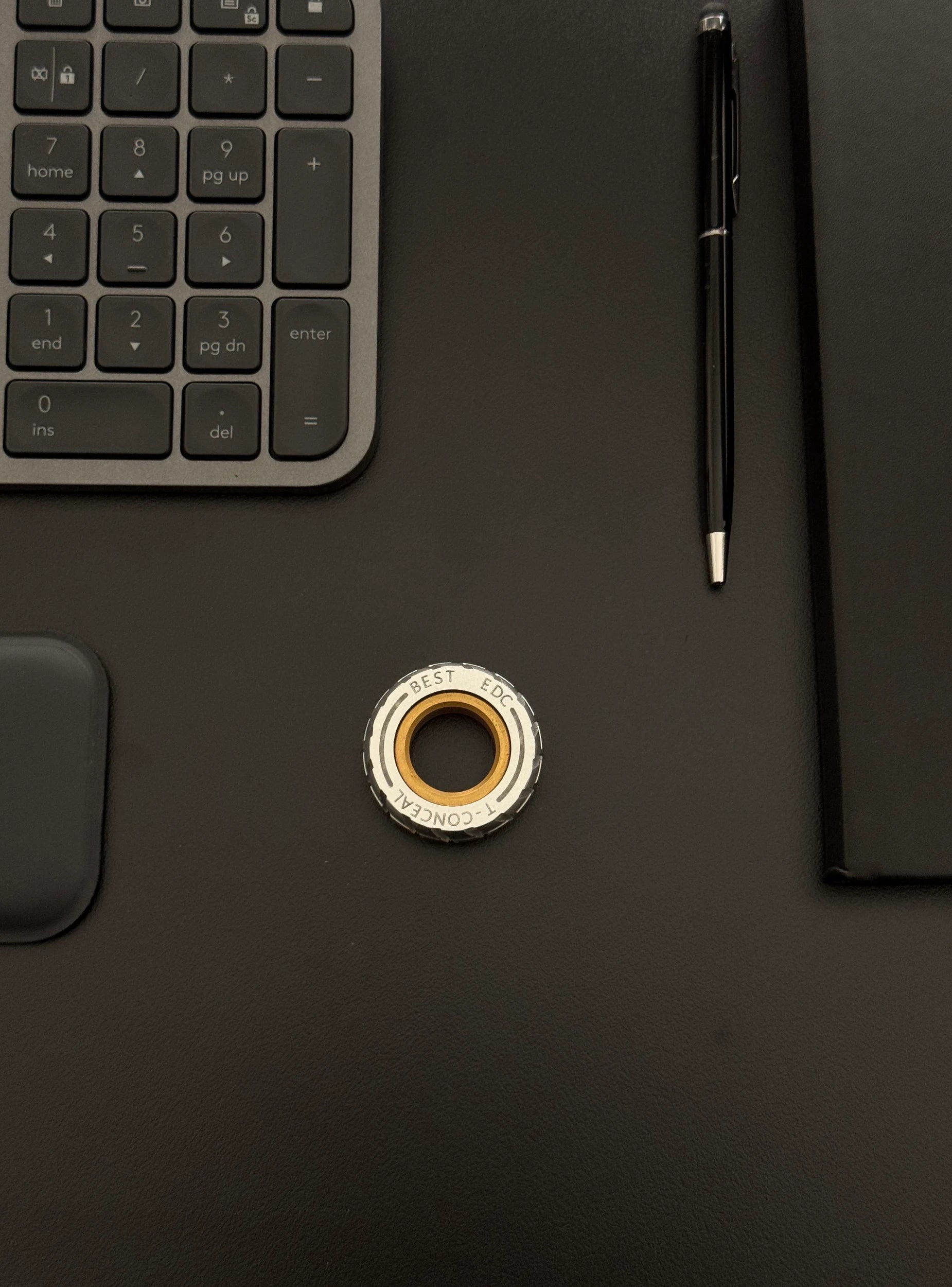 Spinner placed on a desk with a keyboard and notebook, demonstrating its compactness.