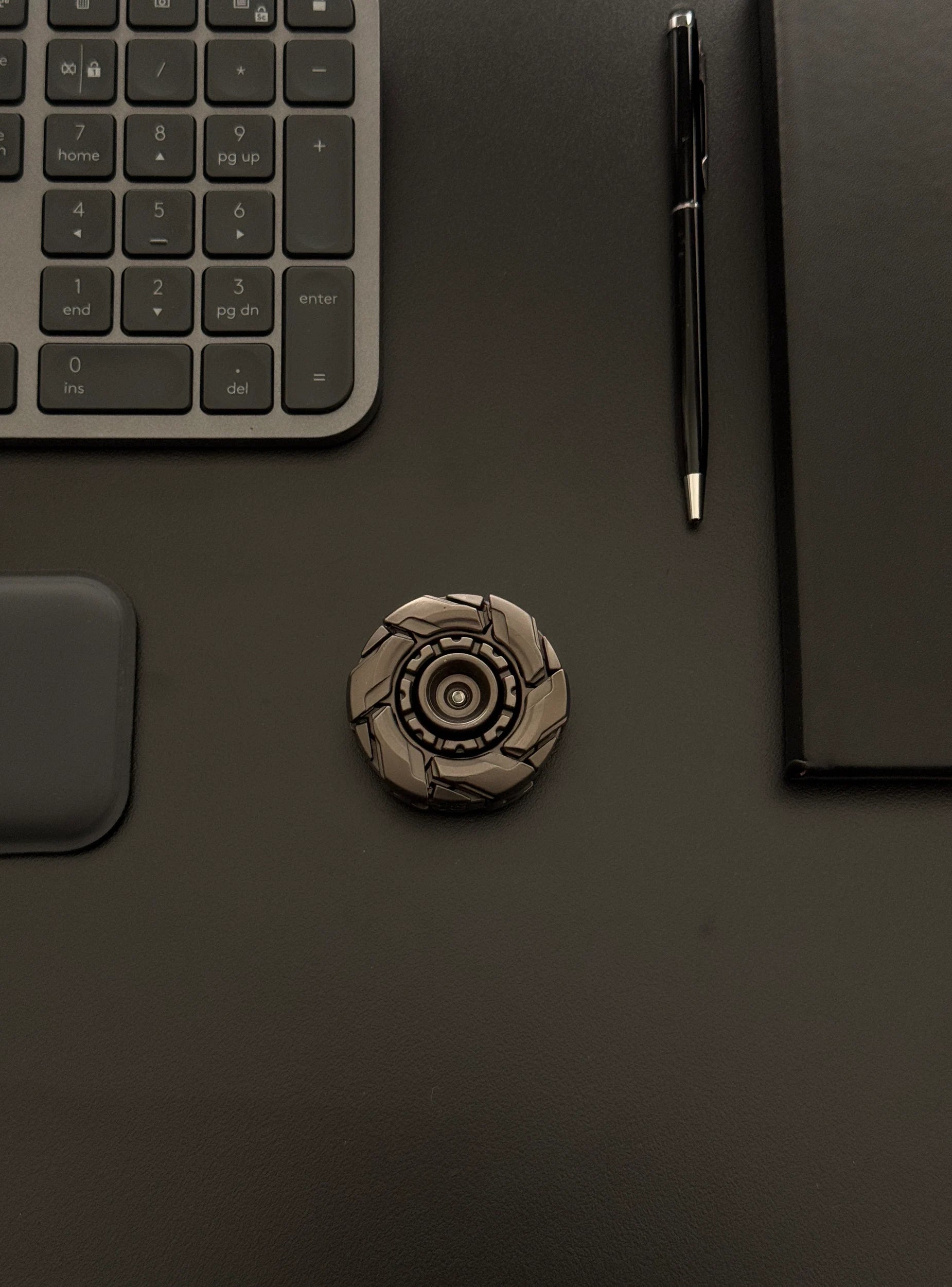 Robust metal fidget toy placed next to work accessories, emphasizing its premium and adult-oriented build
