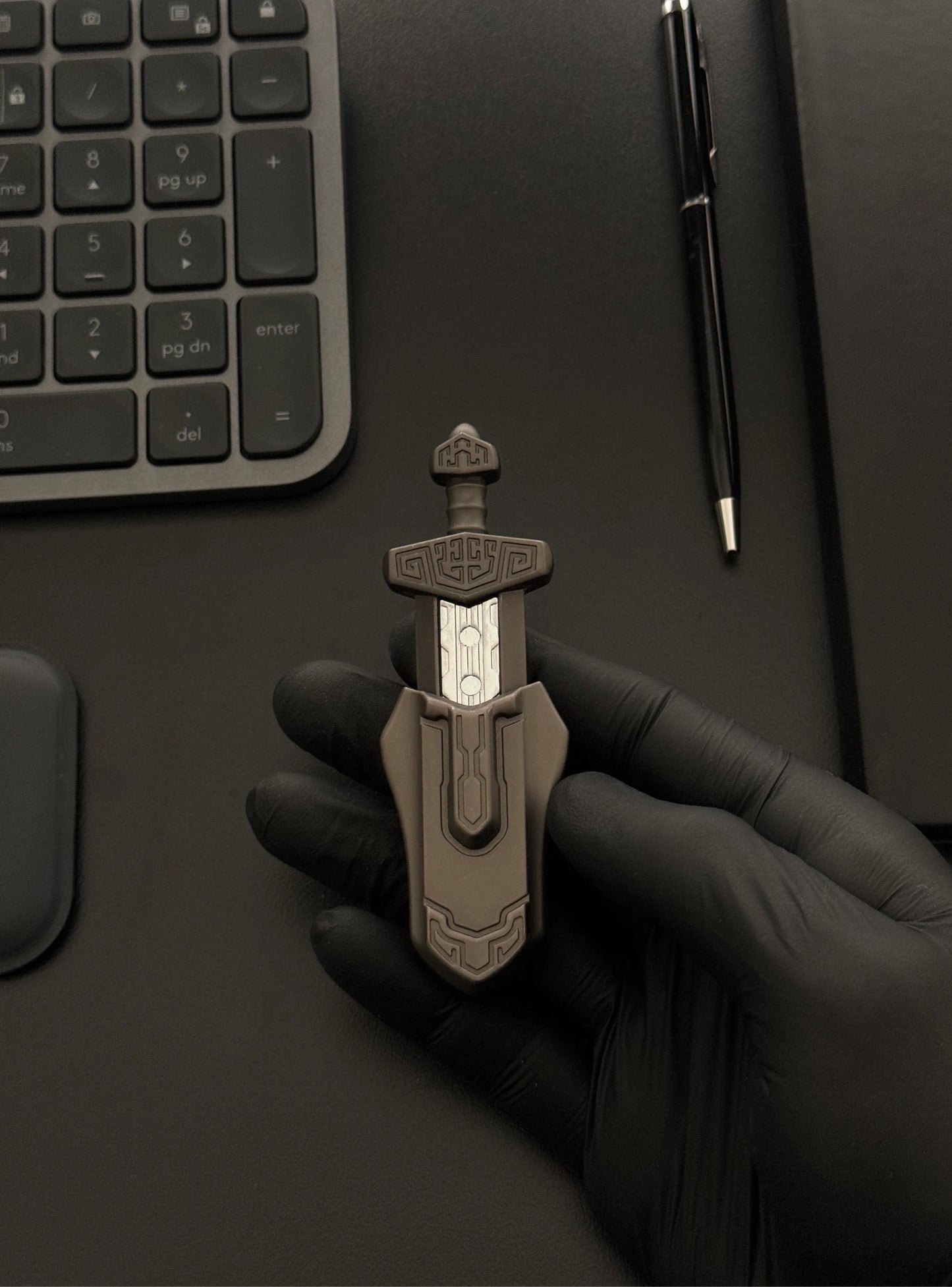 Magnetic Sword Slider placed on a desk with a keyboard and notebook in the background.