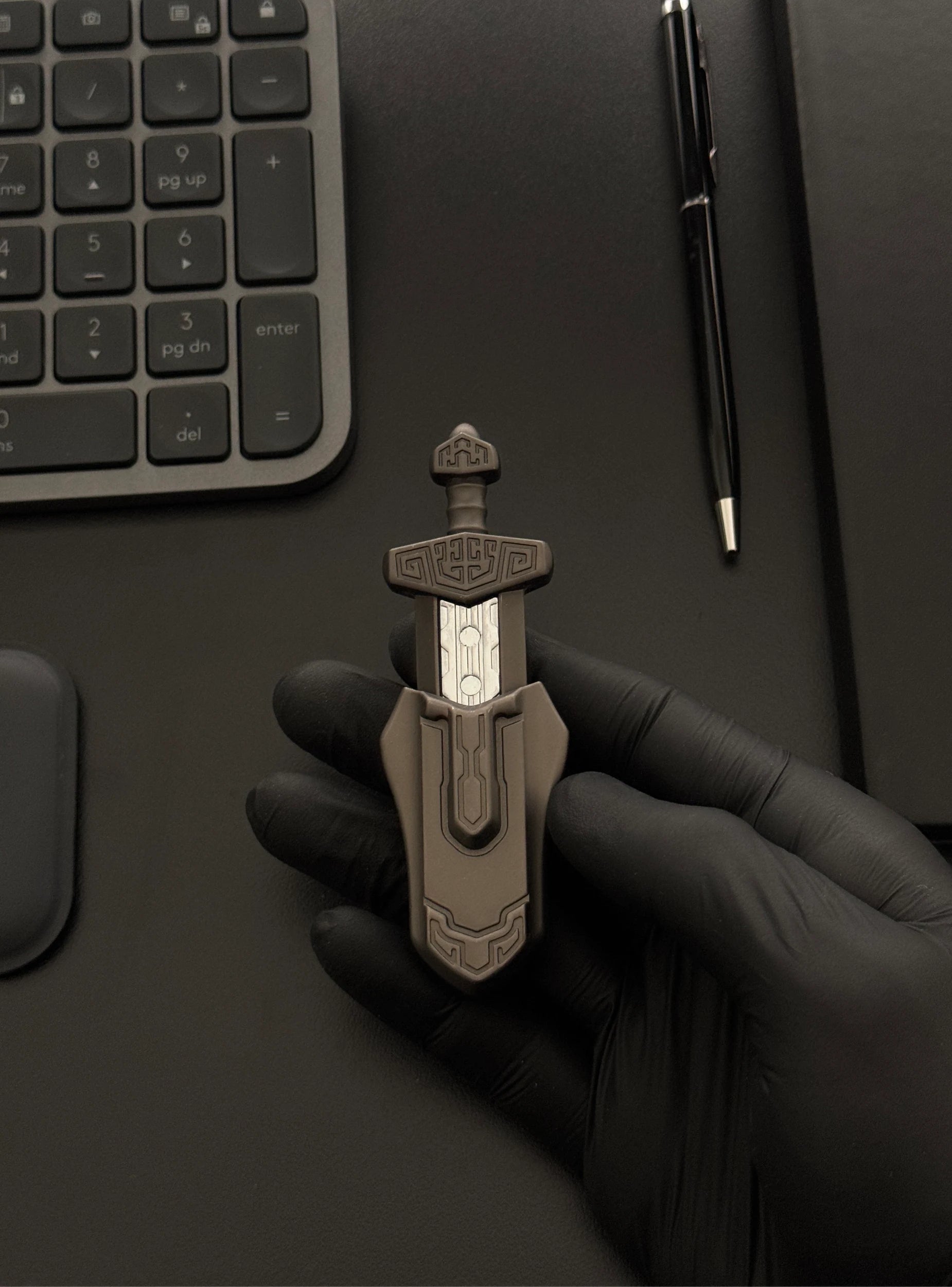 Magnetic Sword Slider placed on a desk with a keyboard and notebook in the background.