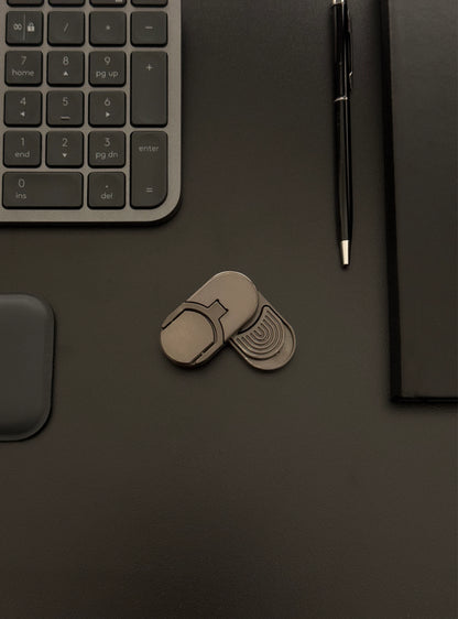 Coin slider fidget toy placed on a desk with a keyboard and notebook, emphasizing its suitability for work environments.​
